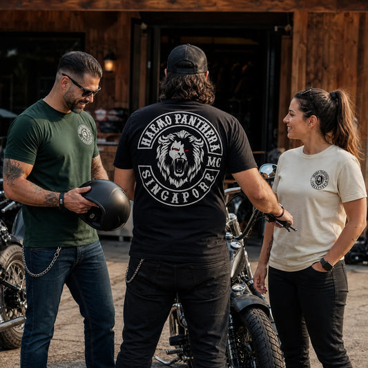 Three Haemo Panthera MC members in classic unisex short-sleeve T-shirts, with two small left-chest logos and one complete large back logo visible at a motorcycle clubhouse.
