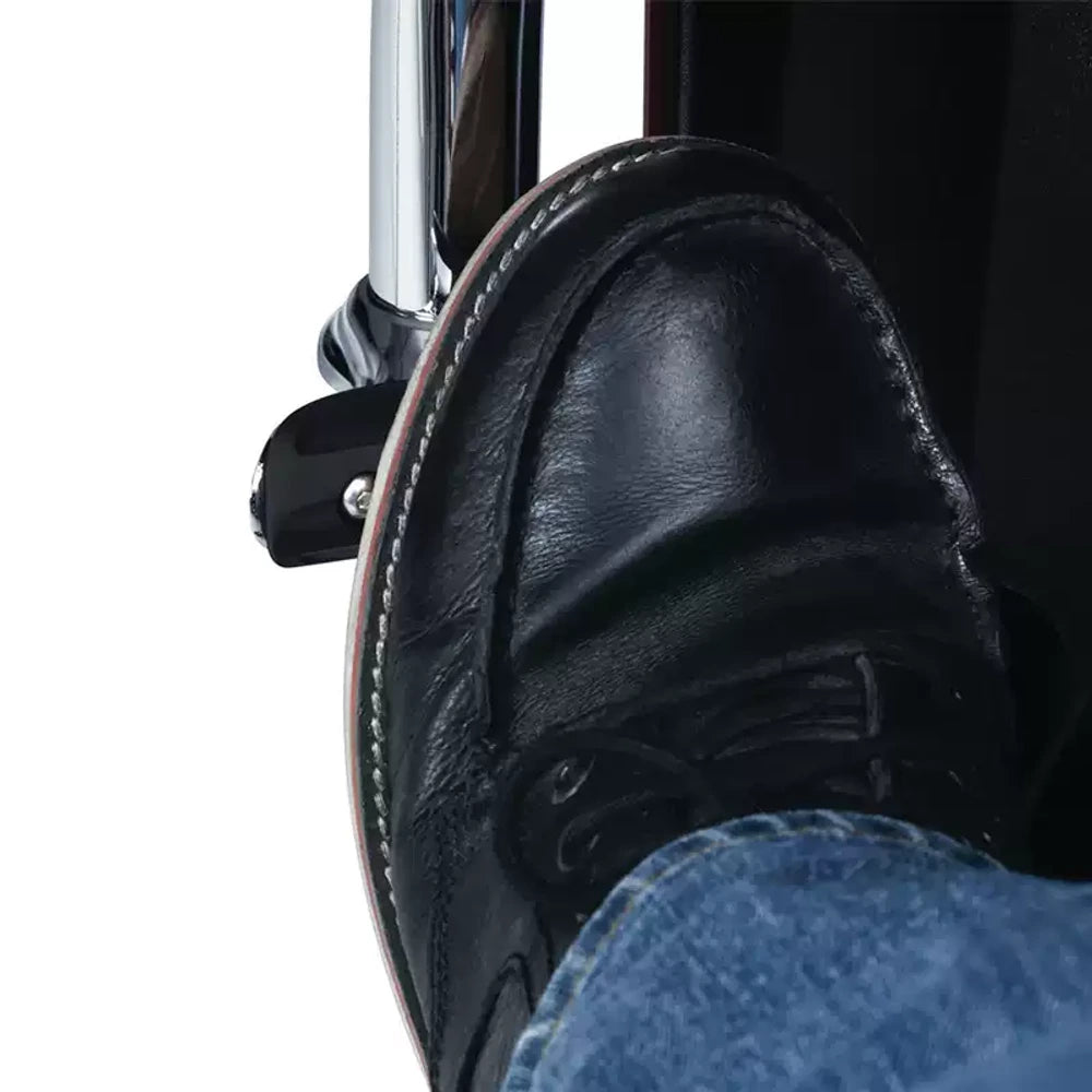 Rider boot resting on a black highway foot peg mounted to an engine guard