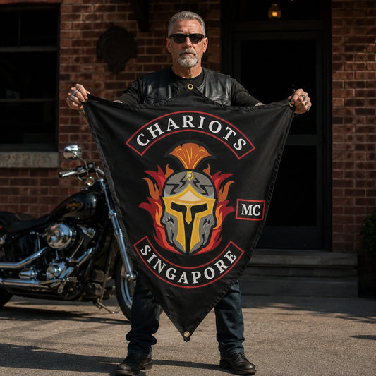 A leather-vested rider displays a fully visible custom diamond-shaped club flag against a brick clubhouse wall.