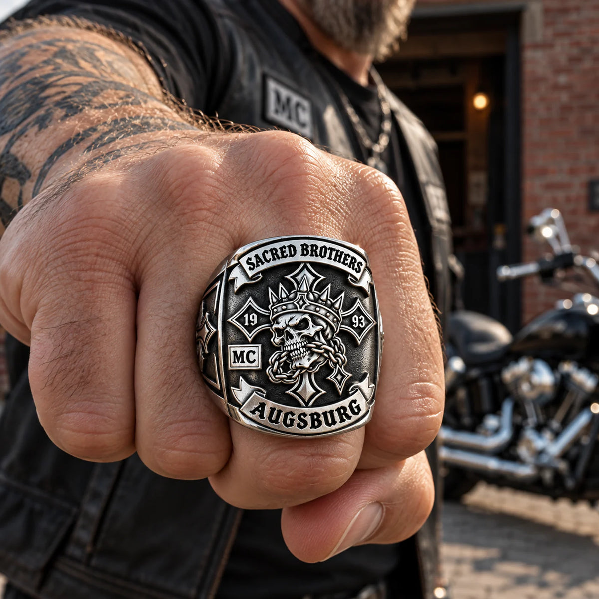 Sacred Brothers club member wearing a custom white copper chapter ring beside a parked motorcycle.