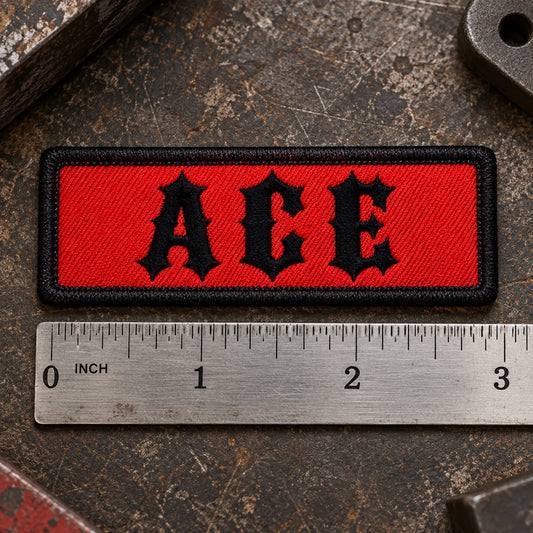 Compact 3 by 1 inch motorcycle name bar beside a precise metal ruler on a leather workbench for clear scale, showing custom motorcycle club name bar patch options.