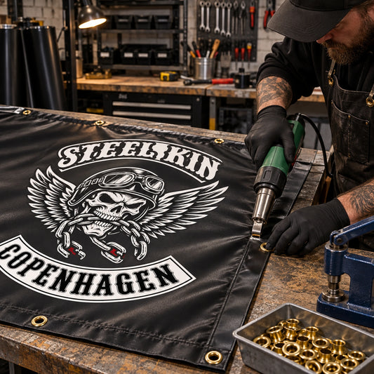 A craftsperson adding reinforced edges and grommets to a custom club event banner.