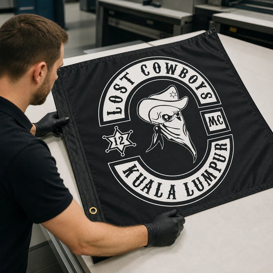 A print technician checks club colors, reinforced edges and grommets on a custom motorcycle club flag.