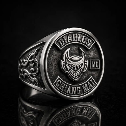 Heavy sterling silver custom motorcycle club ring featuring a sculpted devil face emblem with raised details on a black studio background.