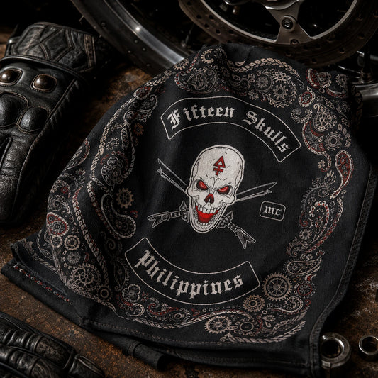 Custom motorcycle club bandana featuring the authorized Fifteen skulls identity in macro textile studio scene showing natural cotton weave, rolled hem and ink penetration beside worn riding gloves.