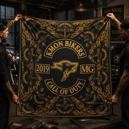 Custom motorcycle club bandana featuring the authorized KMON BIKERS MG identity in edge-to-edge all-over bandana suspended for inspection in a moody print workshop, every corner in frame.
