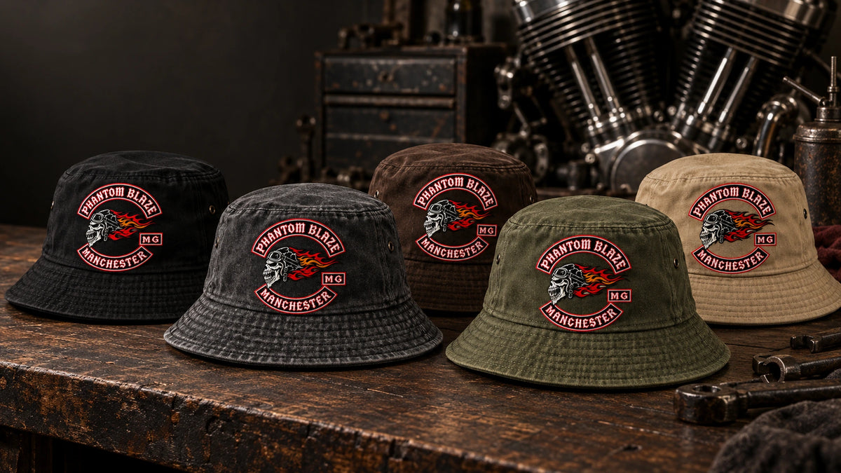 Custom motorcycle club bucket hats in black, charcoal, brown, olive and khaki displayed in a heritage workshop.