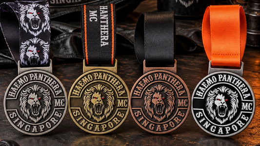 Four solid medals with printed, woven, solid-color and full-color sublimated neck ribbons, presented side by side on a complete dark tabletop. Custom motorcycle club medal.