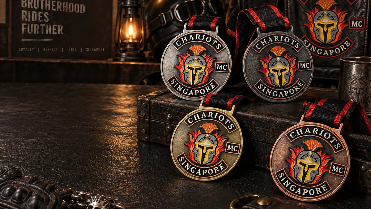 A premium lineup of solid motorcycle club medals in antique silver, gunmetal, antique brass and antique copper with coordinated black and club-color neck ribbons, arranged on a dark leather clubhouse presentation table; wide cinematic composition with clear dark text space on the left. Custom motorcycle club medal.