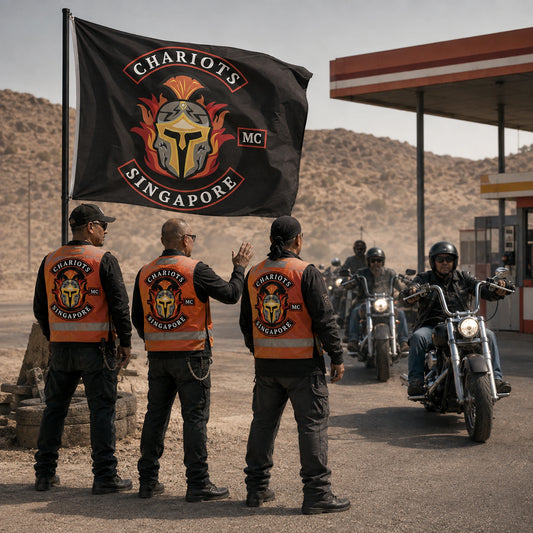 Motorcycle event marshals stand beside a custom club flag at a desert rally checkpoint.