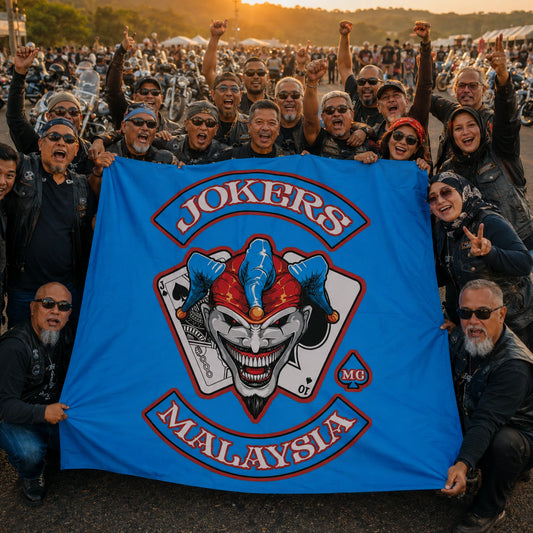 A large motorcycle club group gathers around its custom flag at a golden-hour regional V-twin rally.