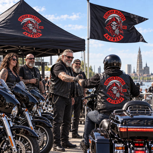 Motorcycle club members greeting a rider beside a custom swallowtail flag at a daytime rally.
