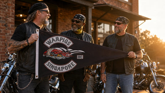 Mature motorcycle club riders display a custom triangle flag beside American V-twin motorcycles outside their clubhouse.