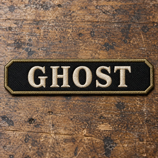 Custom-shaped embroidered name bar with restrained clipped corners, shown alone on textured leather without becoming a curved rocker or oversized badge, showing custom motorcycle club name bar patch options.