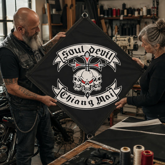 A flag maker and motorcycle rider inspect reinforced edging and hanging loops on a custom diamond club flag.