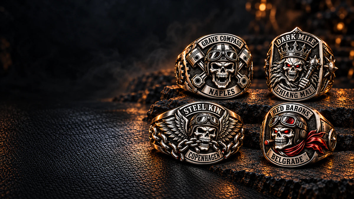 Four distinct custom stainless steel motorcycle club rings displayed in a full-width dark leather and stone jewelry studio.