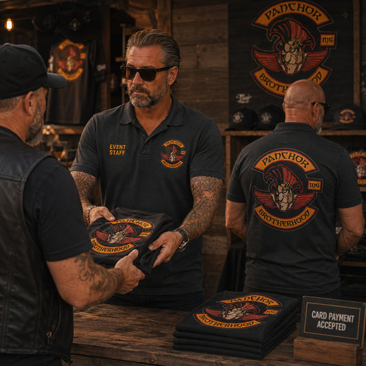 Panchor Brotherhood event staff at a merch station wear charcoal polos with right chest role titles and large back logos.