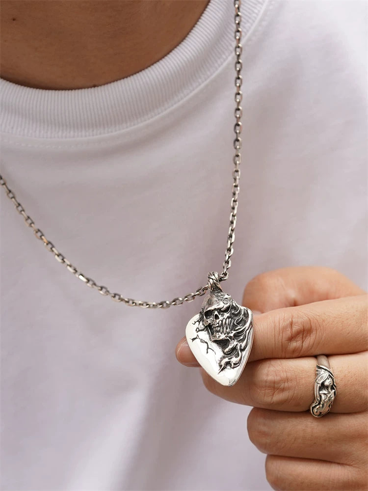 Flaming skull guitar pick biker pendant worn on a chain for scale