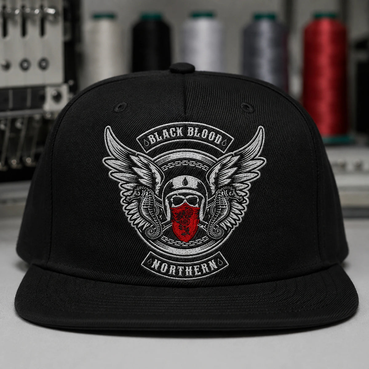 A black motorcycle club flat-brim cap shows finely stitched flat embroidery on its front panel.