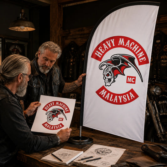 Free Design Support: custom motorcycle club feather flag shown in designer and grey-bearded rider reviewing artwork at a clubhouse worktable.