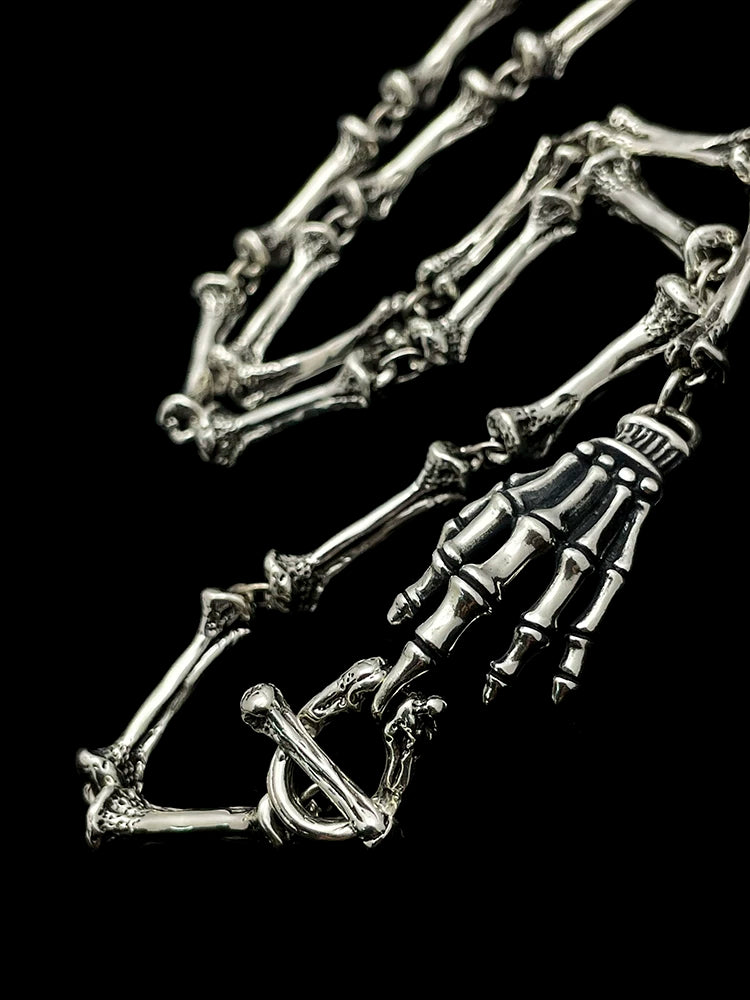 Close-up of skeletal hand clasp and bone-link sterling silver necklace