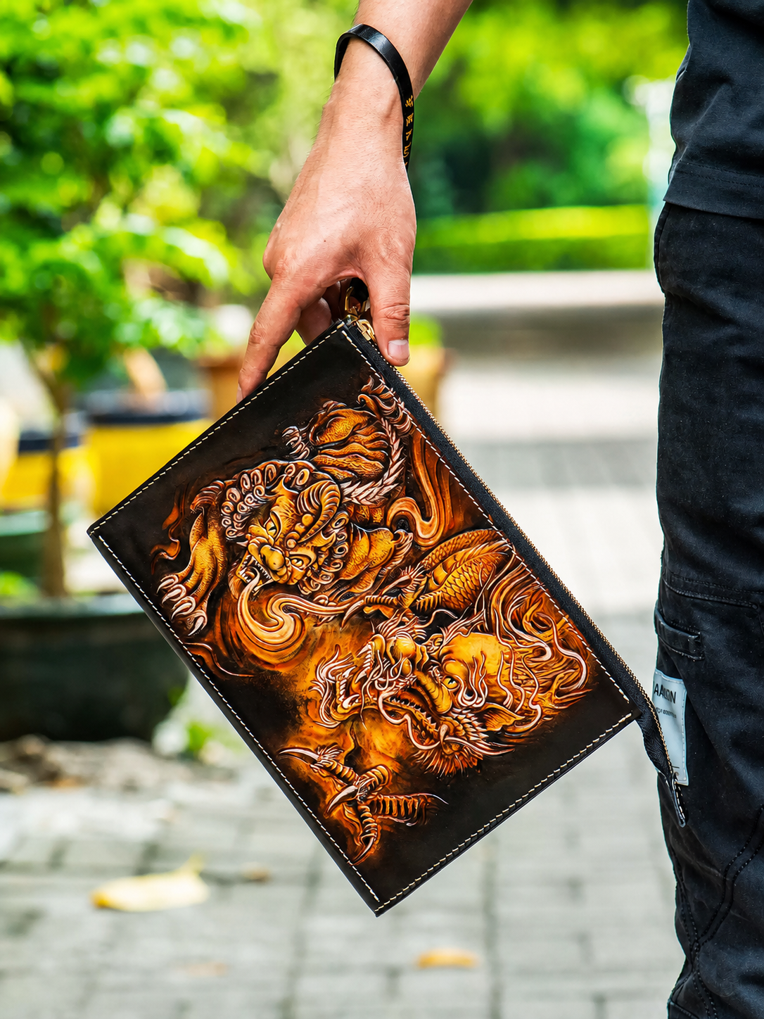 rider carrying a hand-carved leather biker clutch wallet by its wrist strap