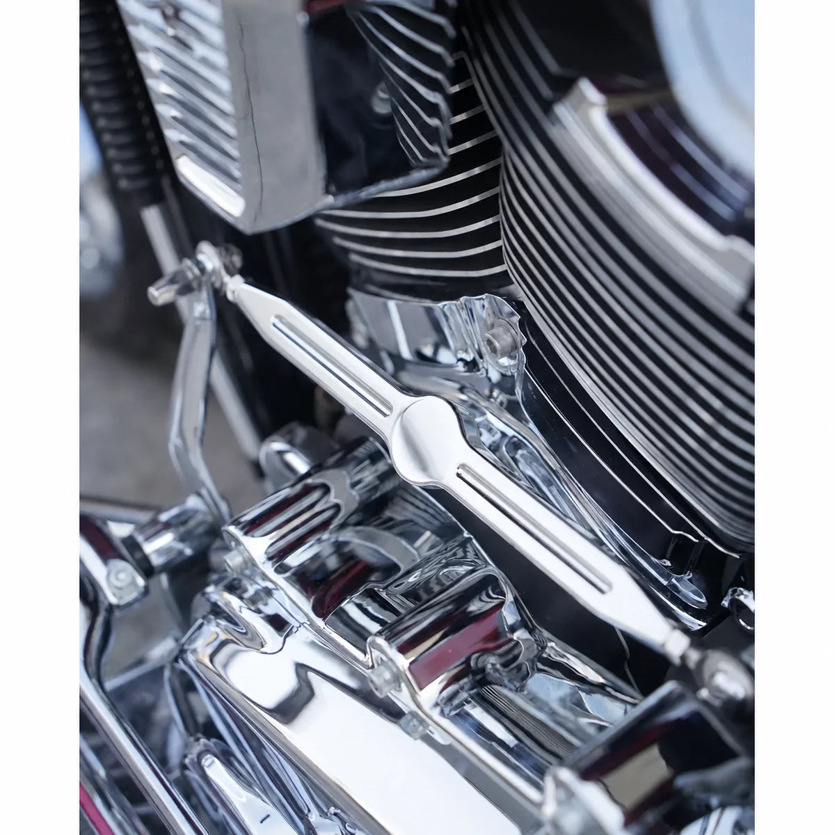 Chrome motorcycle shift linkage rod installed close-up on a compatible Harley engine