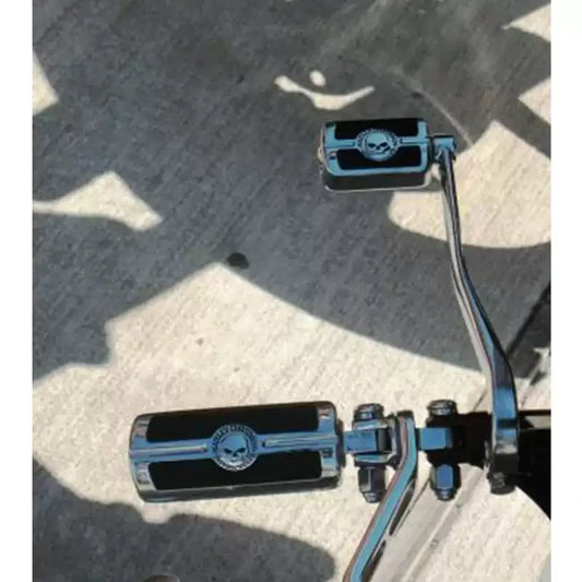 Chrome skull foot pegs installed on a Harley motorcycle, rider view