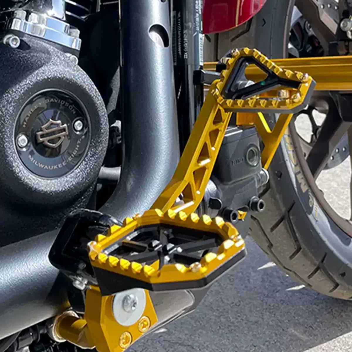 Gold and black PB-style motorcycle foot pegs installed on a Harley motorcycle