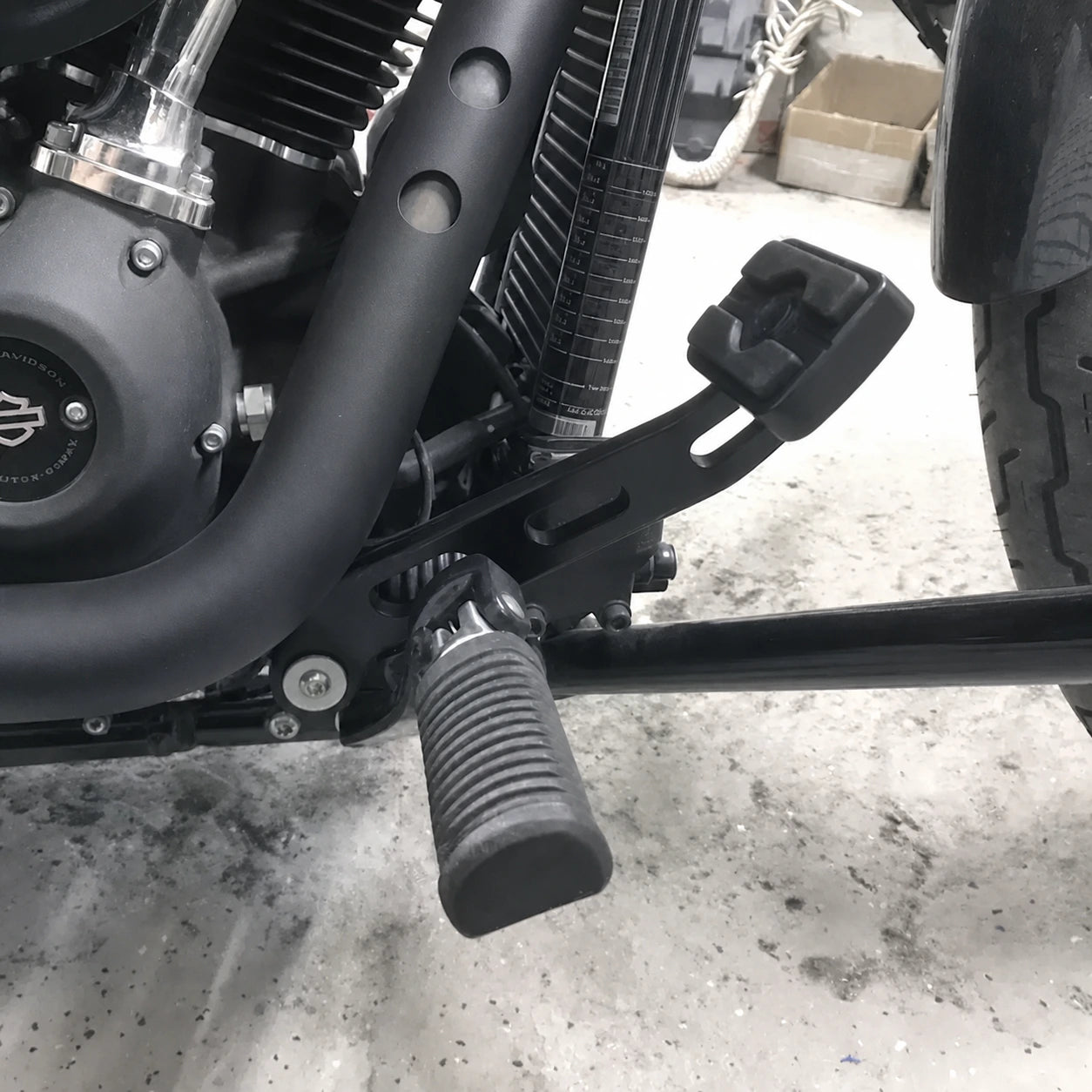 Black forward-control brake lever installed beside the rider foot peg on a Harley Softail