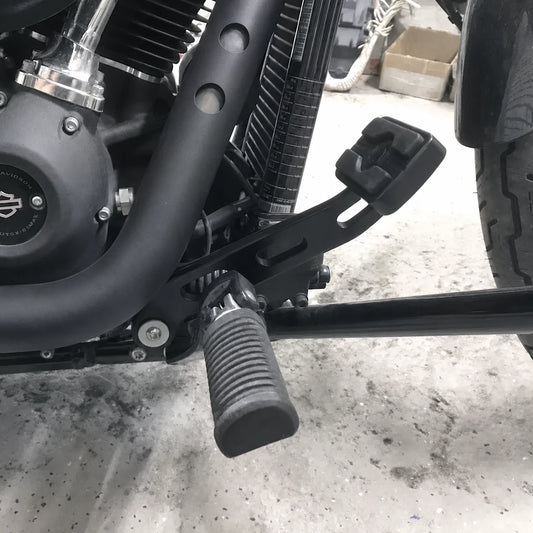 Black forward-control brake lever installed beside the rider foot peg on a Harley Softail