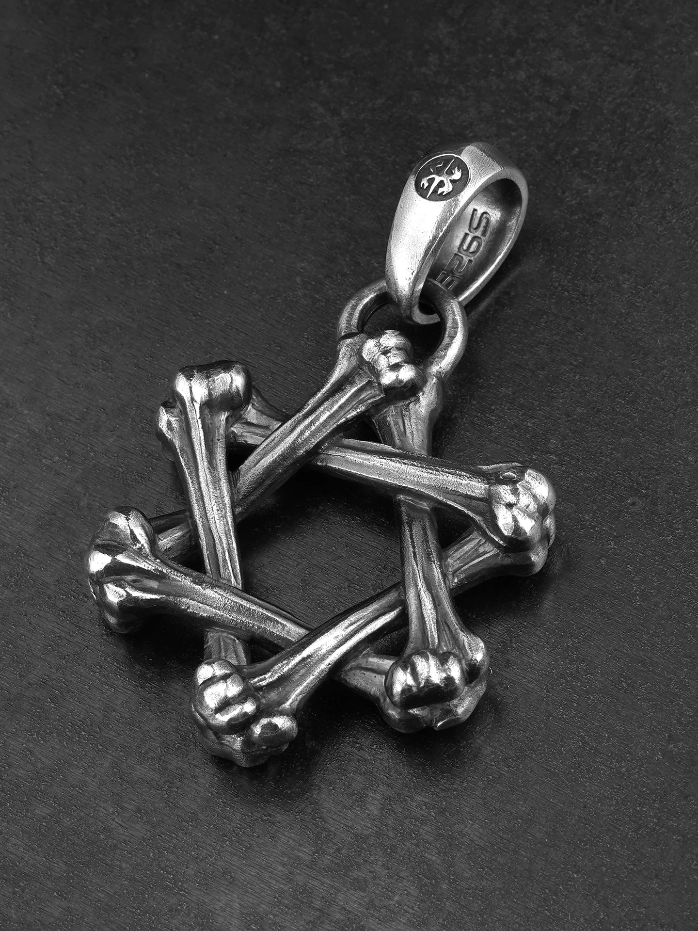 Angled view of crossed bone hexagram silver pendant