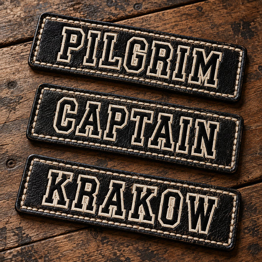 Premium embossed and stitched leather motorcycle club name bars arranged on a worn wooden workbench, showing custom motorcycle club name bar patch options.