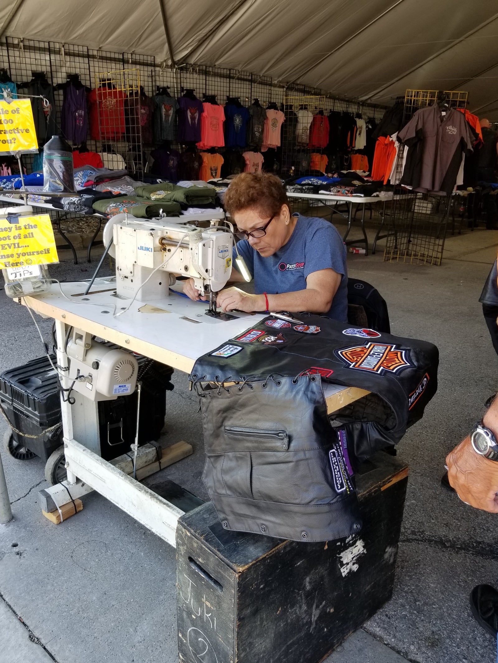 Archive view of a patch worker sewing badges onto a leather vest during the 2019 Sturgis Motorcycle Rally