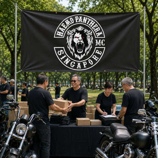 Riders and volunteers using a custom club banner at a motorcycle charity ride.