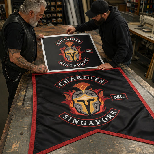 Club representative and designer inspecting custom logo artwork beside a finished swallowtail flag.