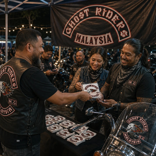 Adult motorcycle club riders receiving commemorative custom stickers at an evening anniversary ride finish checkpoint.