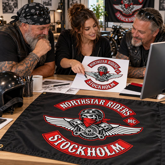 Two mature riders collaborate with a designer on a production-ready custom motorcycle club flag layout.