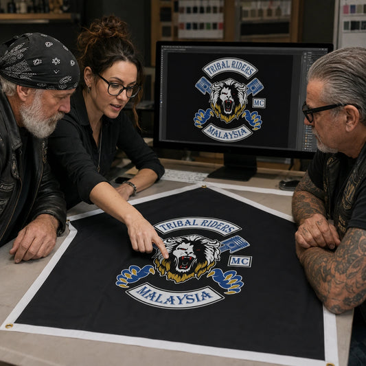 Two mature riders collaborate with a designer on a production-ready custom motorcycle club flag layout.