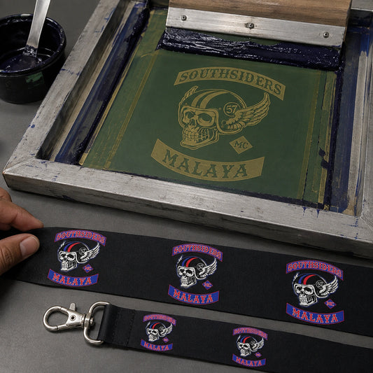 A screen-printing setup beside a finished motorcycle club lanyard with a clear surface-printed logo.