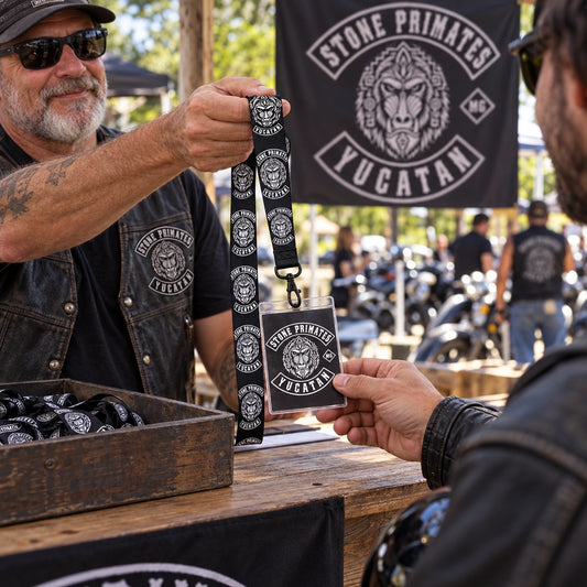 A rally volunteer handing a club-logo lanyard and event credential to an arriving rider.