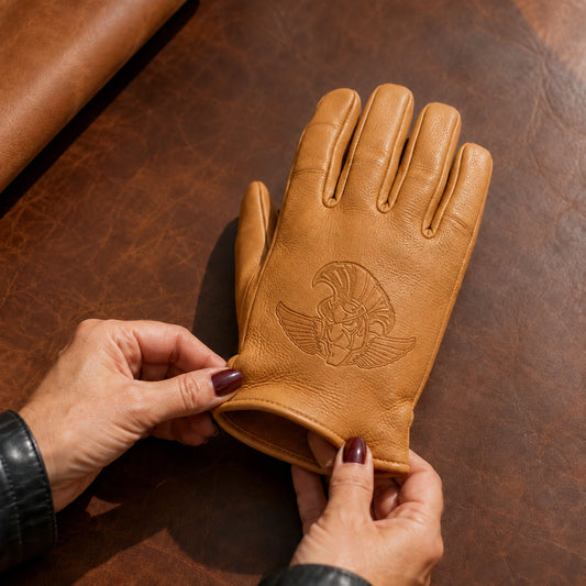 A tan goatskin club glove with a tonal pressed emblem is held beside its supple leather sample.
