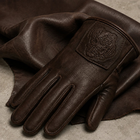 A dark sheepskin club glove with a tonal leather logo patch rests on a matching soft swatch.