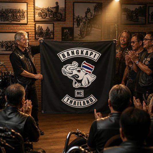 Motorcycle club members applaud as their president unveils a custom square anniversary flag.