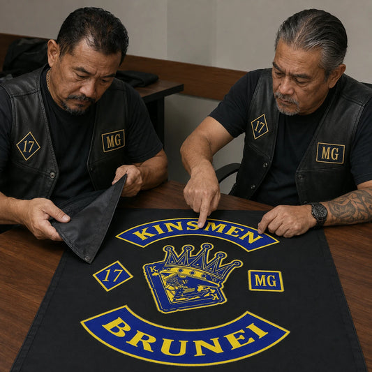 Two motorcycle club officers inspect logo alignment and fabric on a custom square flag proof.