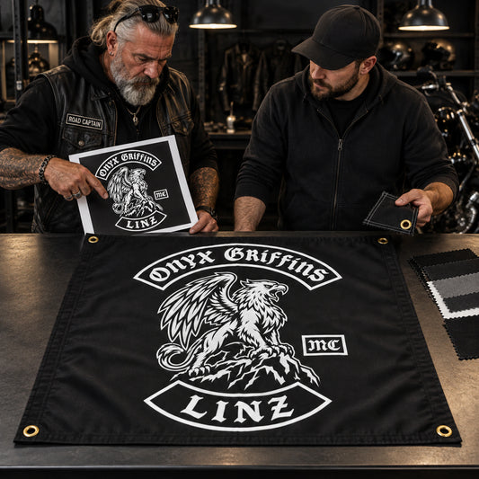 A road captain and print specialist compare artwork with a custom Onyx Griffins motorcycle club square flag.