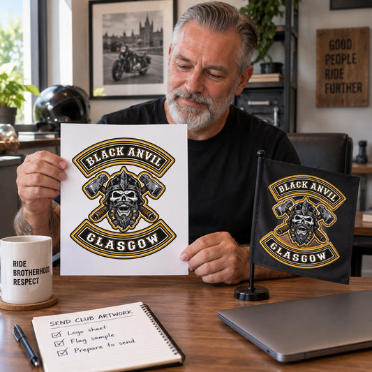 A motorcycle club secretary prepares Black Anvil logo artwork beside a square flag reference.