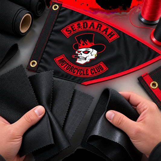 A textile specialist compares durable fabric textures beside a finished motorcycle club triangle flag.