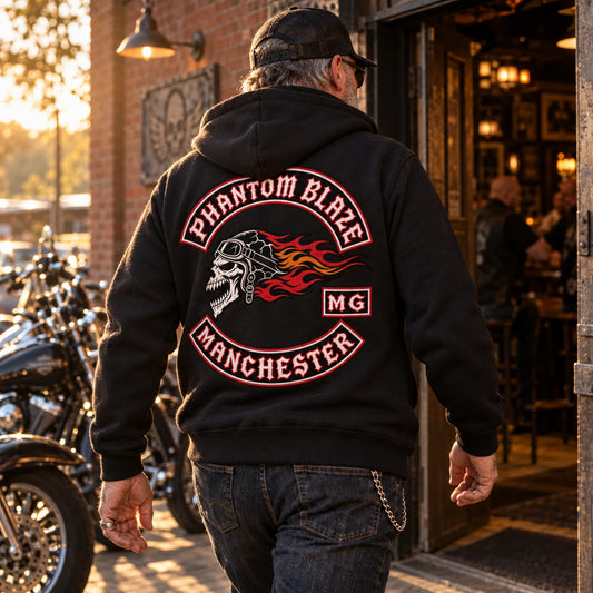 Mature rider entering a brick clubhouse in a black pullover motorcycle club hoodie with authorized Phantom Blaze back artwork.