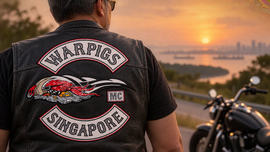 Rider wearing a custom memorial patch on a black leather motorcycle vest beside an open road.